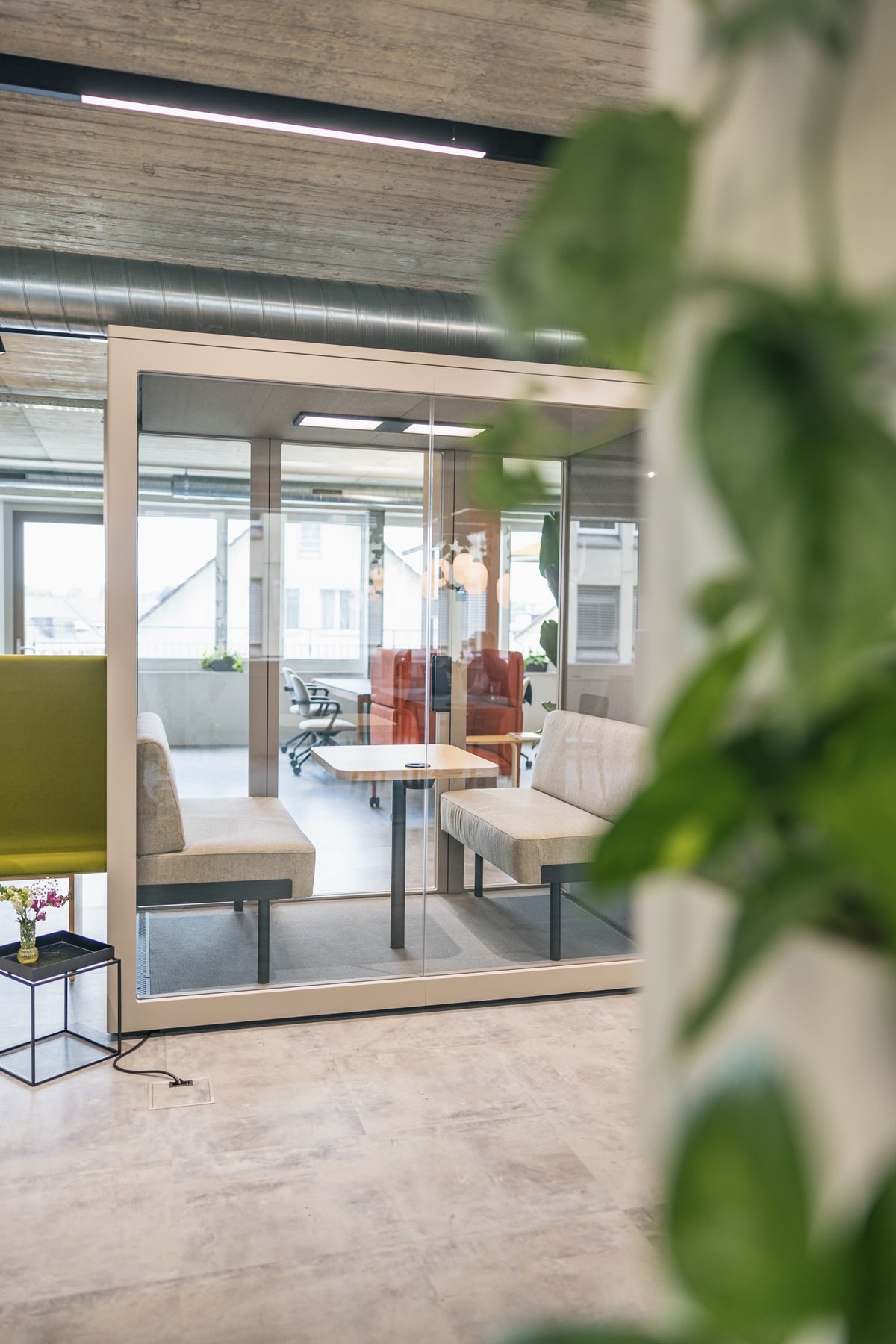 Blick durch Grünpflanzen in einen verglasten Besprechungsraum der Work Factory