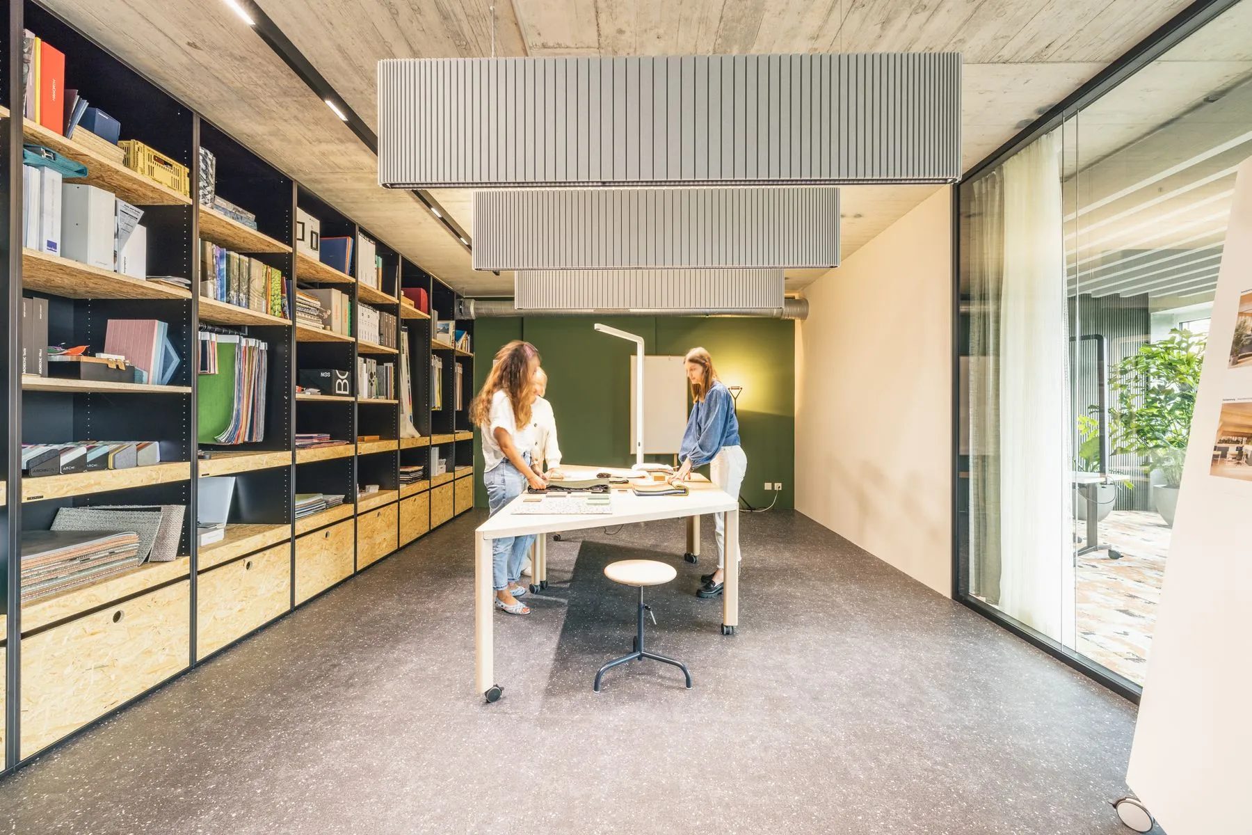 Raum der Work Factory mit grosser Regalwand, zwei Personen an einem Tisch